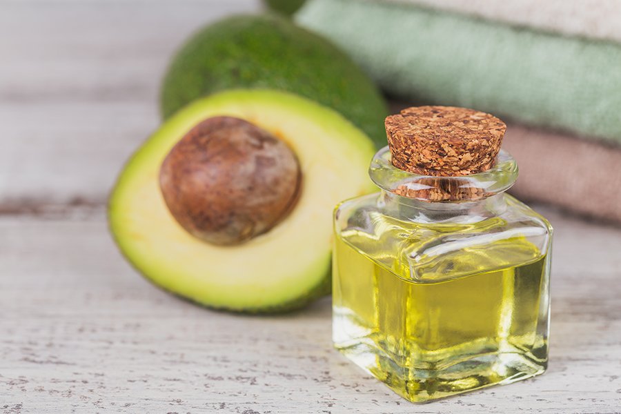 Natural cosmetic oil with avocado on white rustic wooden background. Healthy skin, facial and body care. SPA and sauna concept. Close up